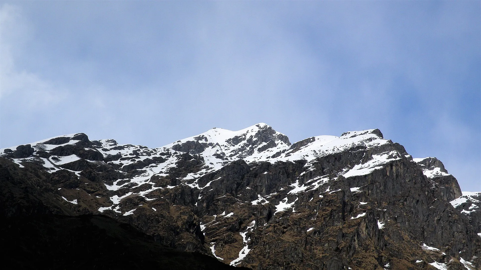 MadTrek guide pausing on a high Himalayan trail with snow peaks behind