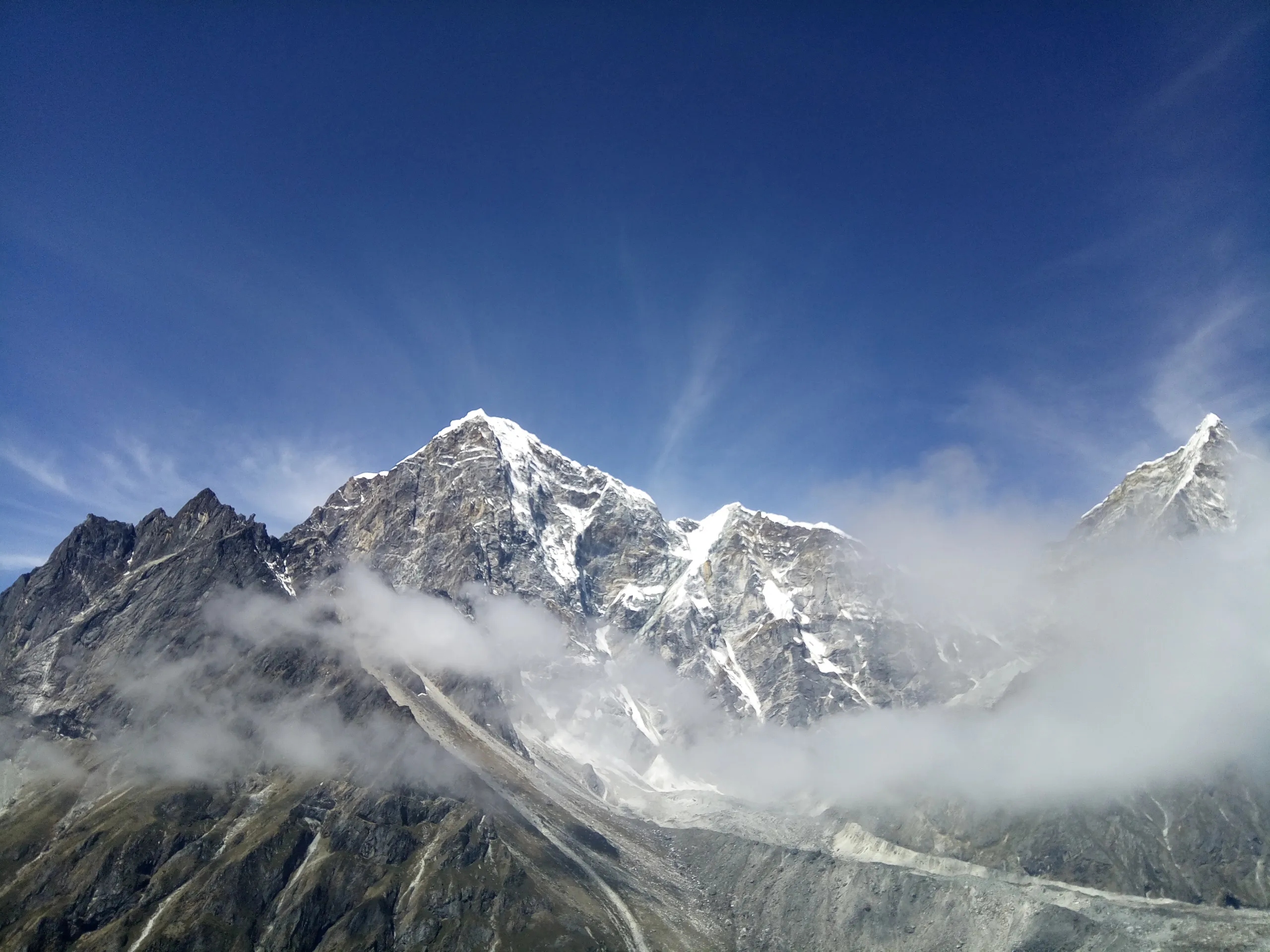 Wide Himalayan valley with a trekking trail winding toward snow peaks